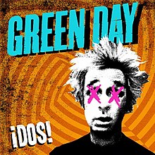 A black-and-white cutout of Mike Dirnt's head, his eyes crossed-out with pink X's, on a geometric, orange striped backdrop. The words "Green Day" are loudly splashed in blue across the top of the cover, while the word "¡Dos!" is sprawled graffiti-style in white in the lower left-hand corner.