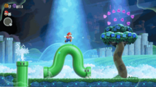 This is a screenshot of Super Mario Bros. Wonder, showcasing its dynamic level design. In the screenshot, Mario is on top of a pipe that has bent in unnatural ways.