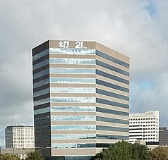 A multi-story stucco and glass office building topped with KTVT and KTXA logo signs featuring the star-11 and star-21.