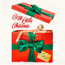 Katy Perry peaking out of a red gift box with green decorating ribbons tied around it.