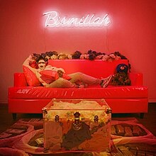 Leikeli47 reclining on a red couch