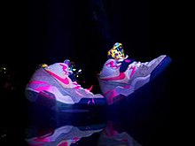 A pair of pink, neon sneakers on a black background