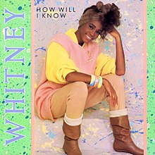 A woman is sitting, with a smile on her face. She is looking forward and her head is resting on her left arm. She is wearing bracelets on her right wrist. Next to her the word "Whitney" is written in medium purple capital letters. The words "How Will I Know" are written near her head.
