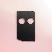 A piece of black plastic on a light pink background