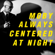 A black-and-white photograph of Moby turned to the side, with his shadow behind him on a wall, overlaid with his name and the title in yellow text