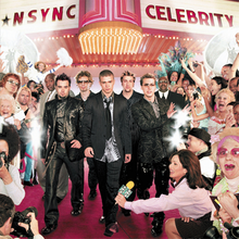 NSYNC is seen walking on a red carpet, surrounded by flashing cameras and a crowd of people.