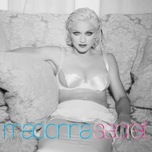 Madonna in a white dress sitting on a sofa and smiling