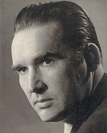 Sepia glamour, three-quarter profile shot of clean-shaven young man with short, oiled, combed-back hair.