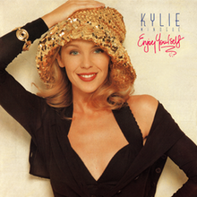Minogue posing with a golden hat and wearing a black blouse