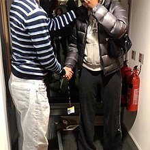 Two people shaking hands in a doorway next to two fire extinguishers
