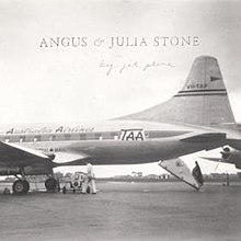 A black and white image of a Trans Australian Airlines Douglas DC-6 parked in the airport apron with its back hatch opened.