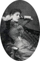 portrait of young white woman with dark hair, leaning back in a chair