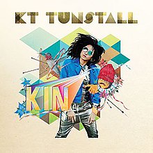 Tunstall stands against a white background covered in colourful drawings. She flips her hair while wearing a blue jacket, sunglasses, and silver trousers. The title "KIN" is written in a stylised font, and the name "KT Tunstall" is placed across the top of the image.