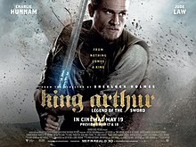 King Arthur wields the sword, Excalibur, as an inscription on it lightly glows with debris hovering around the subjects.