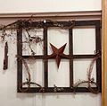 A primitive decoration created using an antique window frame, barn star and pip berry garland