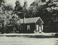 Single-story building in a field, flanked with trees