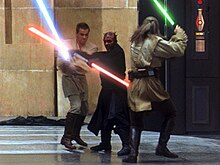 Three men fight with laser swords in an hangar.