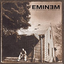 A sepia toned image of Eminem sitting in front of an old house. On the top right is the "EMINEM" logotype with"the marshall mathers lp" immediately below it in a smaller font