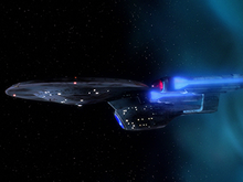 An oblong, blue-grey starship with an oval hull and two flanking, glowing engines