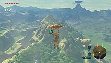 An in-game screenshot of the protagonist Link, paragliding across a vast world.