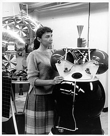 A woman standing near a satellite