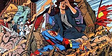 A dark-haired woman, kneeling in ruins, cries over the battered corpse of Superman.