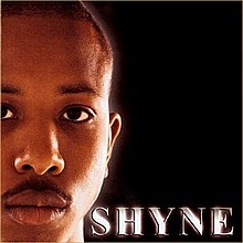 The cover features a close-up of Shyne's face against a black background. The artist's name appears below him, colored in platinum.