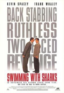 A man towering over another shouting down at him. The words "Swimming with Sharks" filling the background