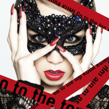 A woman wearing a black bejewelled mask on her face, surrounded by red tape that says "Koda Kumi" and "Go to the Top"