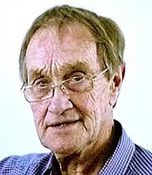 Colour Press photo of a clean-shaven, very elderly, bespectacled man, with sandy-coloured hair.