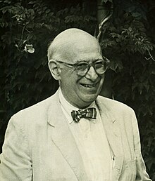 Weinberg with a big grin on his face, wearing a light-colored suit, bow-tie and horn rimmed glasses.