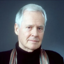 Headshot of an older man wearing a scarf and black shirt