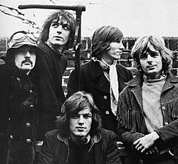 A black-and-white photo of the five band members standing in front of a brick wall in 1968.