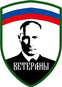 The Logo and patch of the Redut formation "Veterany", with the Russian tricolour at the top horizontally, the edges being green and the below part with white background and a black portrait of Putin in the middle, with the text "Veterany" or "Veterans" written below him.