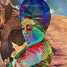A multi-colored photo of Wilson's face superimposed on a desert scene at night