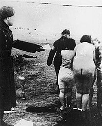 A Latvian guard leads Jewish women to the execution site