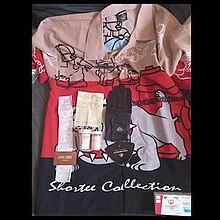 A photo of belongings on top of a shirt depicting a bulldog urinating on a fire hydrant. The belongings are a glove, receipts, a visit card, and two pill bottles and a prescription box, the latter three labelled with the name Aubrey Graham.