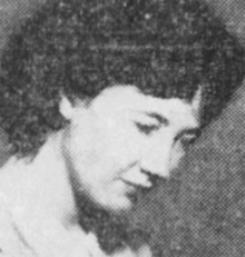 A young white woman with dark hair, gaze cast downward