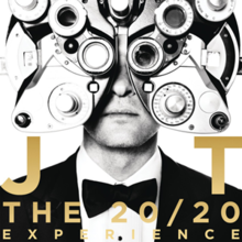 Black and white photo of a man, wearing a suit and bowtie, facing forward - the upper half of his head is covered by a phoropter - the background is entirely white. The lower half of the image features golden text reading "JT" and "THE 20/20 EXPERIENCE".