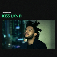 The cover features The Weeknd in his iconic dredlocks hairstyle looking directly at the viewer. A skyline is seen as a backdrop behind the windows. The words "KISS LAND" appears in large green letters in a different font.