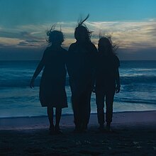 Three silhouettes of women standing on the beach