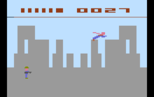 Pixel graphic image that represents a grey city skyline. A blue and red stick figure flies over the city.