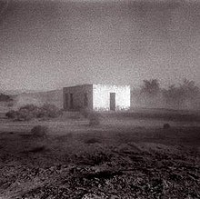 A grainy black-and-white photo of a building in the middle of a desert.