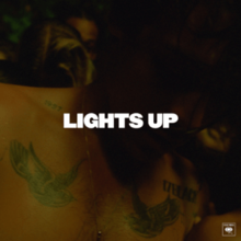 A dimly lit photo of Harry Styles showing his bare chest with two tattoos below each shoulder. The title of the song "Lights Up" is written in all caps in white at the center of the photo.