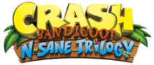 Crash Bandicoot: N. Sane Trilogy est inscrit sur trois ligne, en jaune, marron et bleu, avec en fond des planches de bois et quelques feuilles à chaque extrémités.