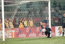 Um goleiro defendendo uma bola pênalti usando a sua mão direita