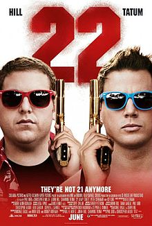 The faces of two men wearing colorful sunglasses, and holding guns up beside their faces. Above them the number '22' in red.