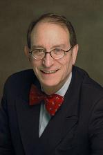 David S. Rosenblatt wearing a white shirt and dark blazer with red bowtie, grinning directly at camera