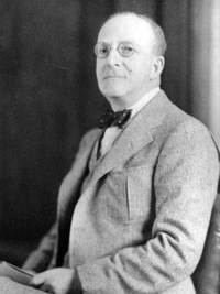 Black and white photo of Hyman wearing a grey suit and black bow tie