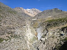 Steam plume emanates from the bottom of a narrow valley in the mountains